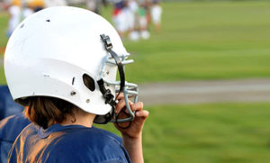 child in a blue jersey and a white football helmet on a football field
