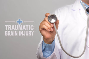 Doctor holding a stethoscope with "traumatic brain injury" text