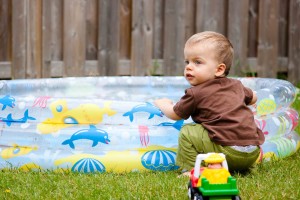 Child squatting near a kiddie pool in the backyard