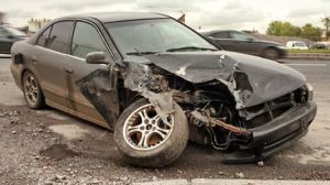Black sedan that has sustained serious damage during a car accident